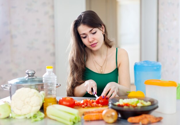 mulher bonita que cozinha salada vegetariana