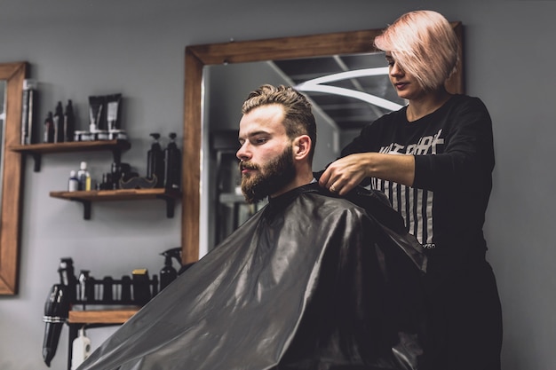 Mulher bonita que prepara o cliente na barbearia