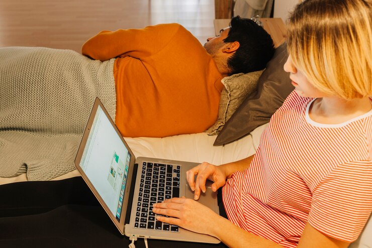 Foto grátis mulher bonita que procura um laptop perto do homem dormindo