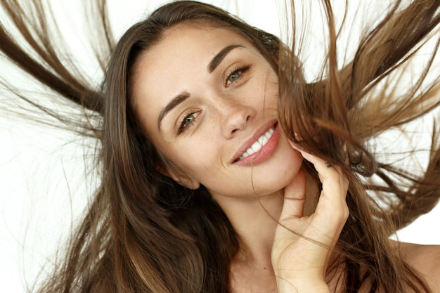 Mulher bonita sacode o cabelo no fundo branco