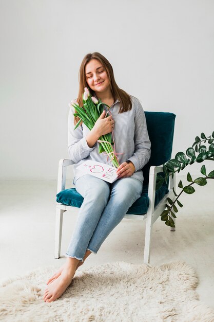 Mulher bonita sentada com tulipas e cartão