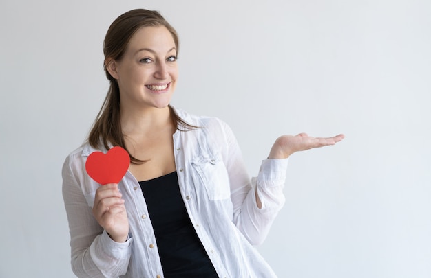 Mulher bonita sorridente segurando coração de papel e espaço vazio