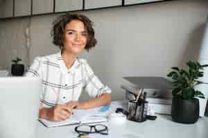 Foto grátis mulher bonita sorridente, trabalhando junto à mesa