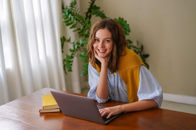 Mulher bonita trabalhando em seu escritório em casa, sorrindo, aproveitando o tempo em sua sala de estar.