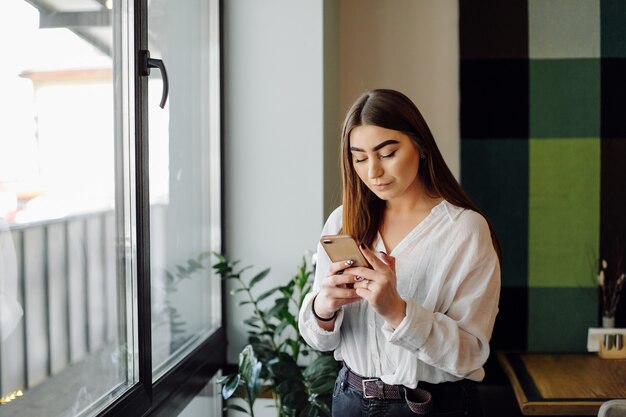 Mulher bonita trabalhando em seu laptop e telefone em um elegante restaurante urbano