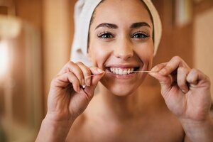 Mulher bonita usando fio dental e limpando os dentes no banheiro