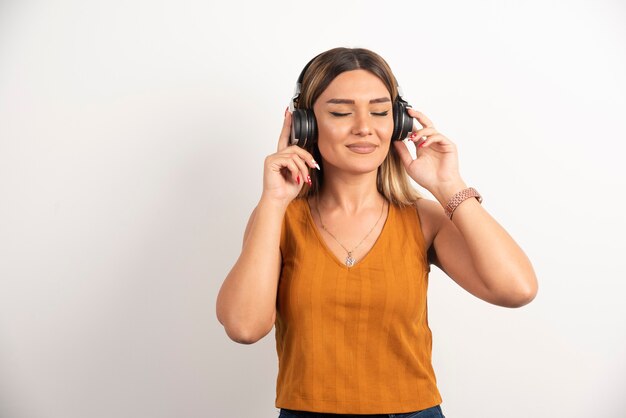 Mulher bonita usando fones de ouvido em fundo branco.