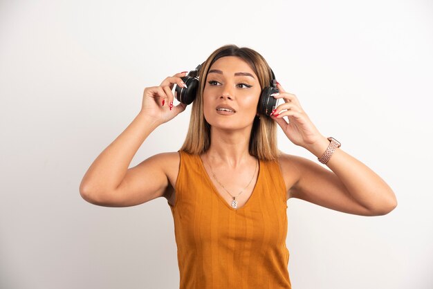 Mulher bonita usando fones de ouvido em fundo branco.