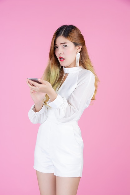 Mulher bonita, vestido branco mostrando o telefone e o humor do rosto