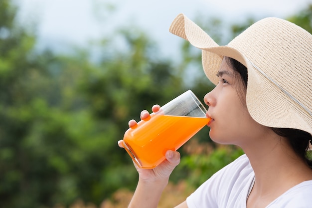 Mulher bonita, vestindo uma camiseta branca, segurando um copo de suco de laranja