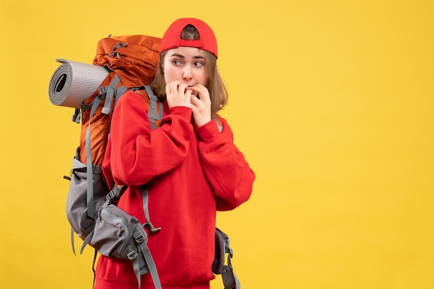 Mulher bonita viajante com mochila vermelha em pé na parede amarela