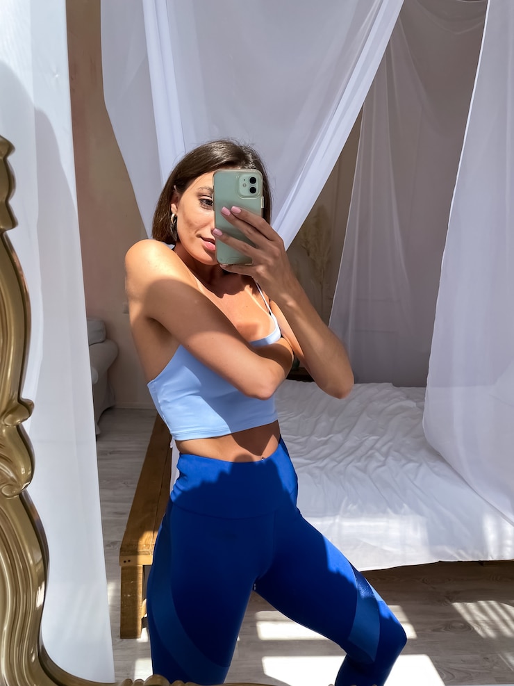 Foto grátis mulher bronzeada em forma em roupas esportivas, corpo perfeito, motivação abdominal, em casa tira uma foto selfie no telefone no espelho