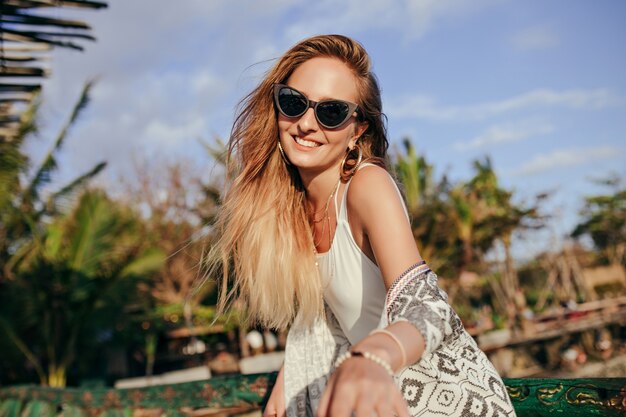 Mulher bronzeada fascinante rindo da natureza. mulher de óculos de sol pretos da moda, expressando felicidade em um bom dia no resort.