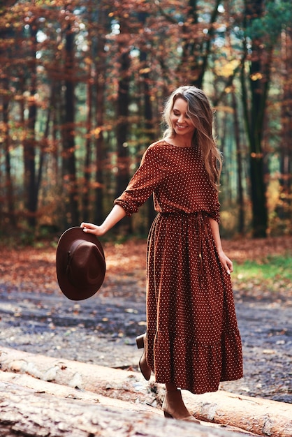 Mulher caminhando na floresta com o chapéu na mão