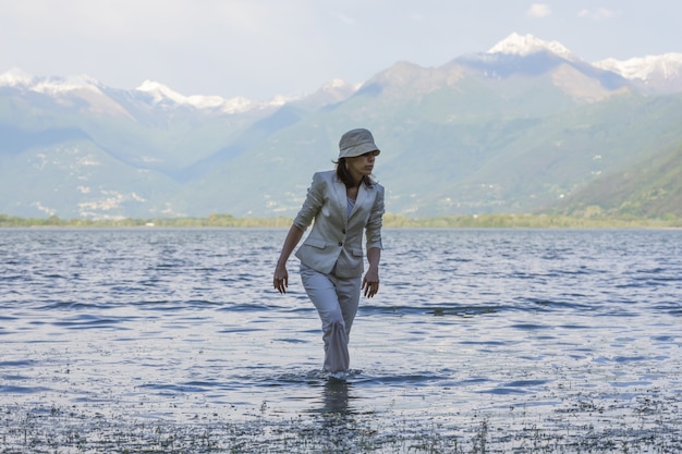 Mulher caminhando no lago com montanhas altas ao fundo