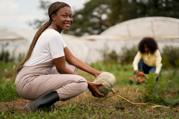 Foto grátis mulher camponesa sorridente de tiro completo trabalhando