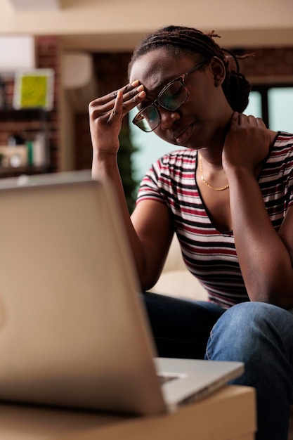 Mulher cansada com enxaqueca, sofrendo de dor de cabeça, tocando a testa com os dedos, esfregando o pescoço. Pessoa exausta com dor de cabeça se sentindo mal, freelancer sobrecarregado e estressado