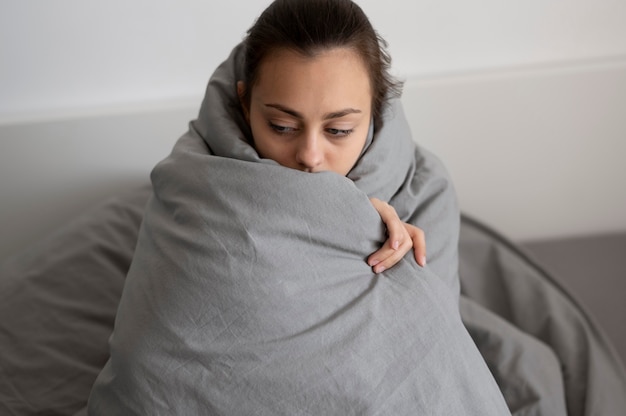Foto grátis mulher cansada com tiro médio cobrindo com cobertor