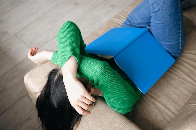 Foto grátis mulher cansada dormindo no sofá com o conceito de excesso de trabalho do bloco de notas