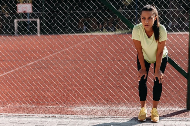 Mulher cansada tendo pausa após treino ao ar livre