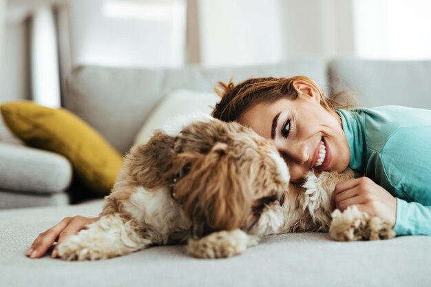 Mulher carinhosa abraçando seu cachorro enquanto relaxa em casa