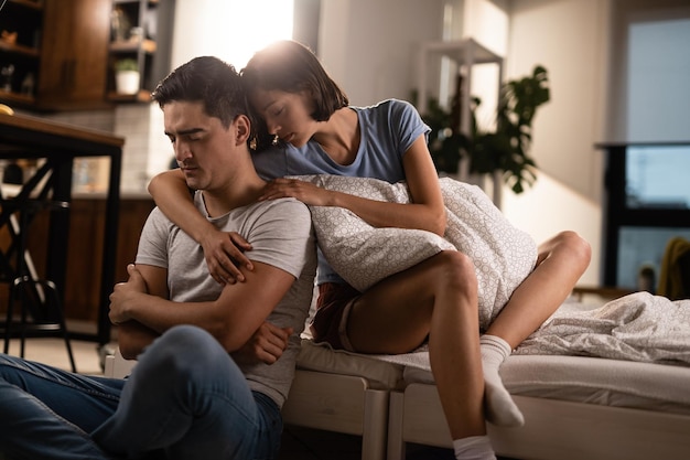 Foto grátis mulher carinhosa abraçando seu namorado triste e consolando-o após a discussão no quarto