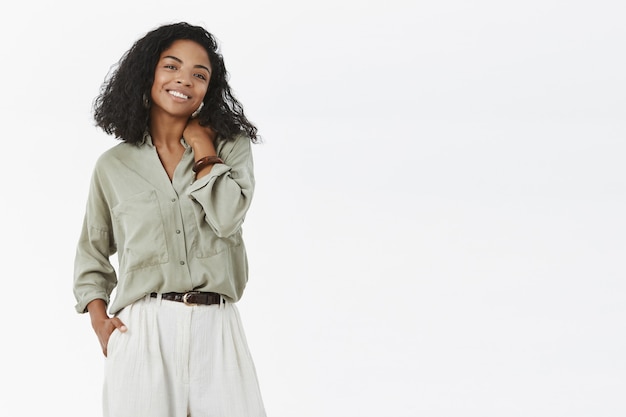 Foto grátis mulher carismática, elegante e criativa de pele escura tocando o pescoço e sorrindo deliciada