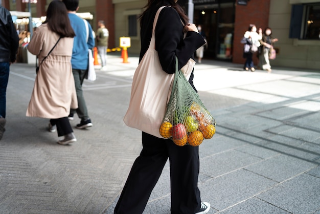 Mulher carregando bolsa com vista lateral de frutas