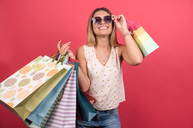 Mulher carregando sacolas de compras, segurando os óculos.