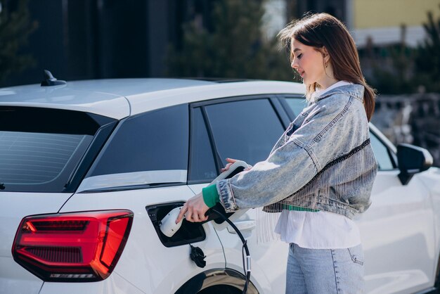 Mulher carregando seu carro elétrico com pistola de carregamento