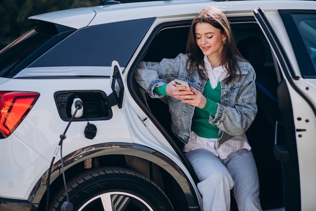 Mulher carregando seu carro elétrico com pistola de carregamento