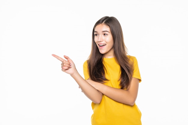 Mulher casual, apontando para o lado e sorrindo sobre parede branca