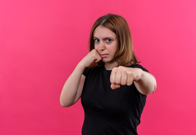 Mulher casual jovem confiante esticando o punho e colocando outro na bochecha em um espaço rosa isolado com espaço de cópia