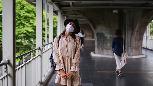 Mulher caucasiana, andando no metrô, atravessando a máscara médica enquanto pandemia na cidade de Bangkok.