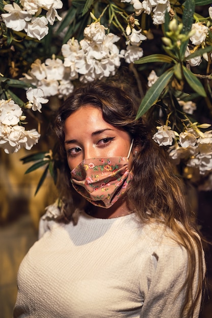 Mulher caucasiana bronzeada usando uma máscara floral em um parque de diversões