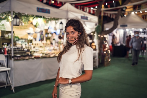 Mulher caucasiana bronzeada usando uma máscara floral em um parque de diversões