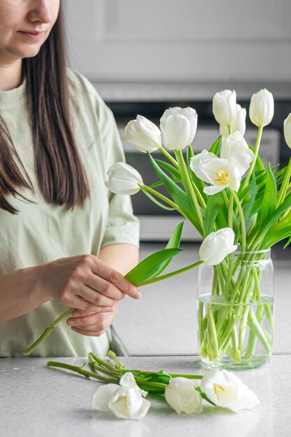 Mulher caucasiana colocando tulipas brancas frescas no vaso
