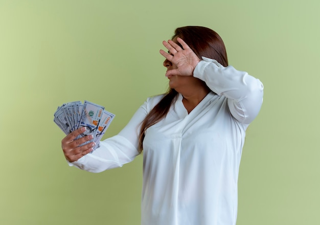 Foto grátis mulher caucasiana de meia-idade casual segurando dinheiro e cobrindo o rosto com a mão