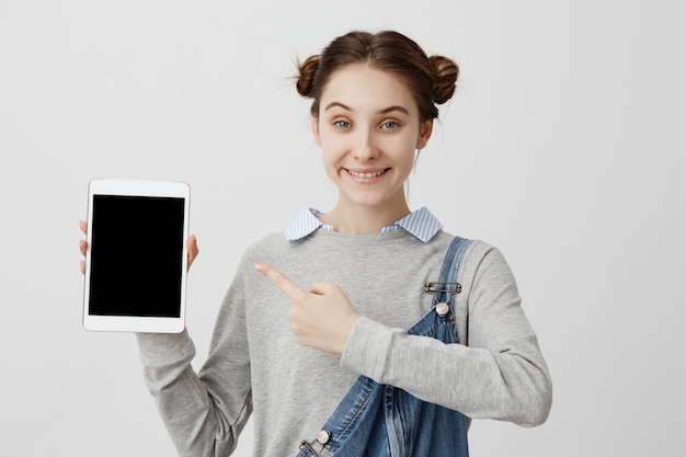 Foto grátis mulher caucasiana em jeans casual, demonstrando modernas técnicas da moda na mão com um sorriso. tiro na cabeça do cliente feliz feminino, sentindo-se satisfeito com a tão esperada compra. marketing, vendas