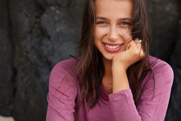 Foto grátis mulher caucasiana feliz com expressão satisfeita, parece alegre, tem olhos verdes, cabelo escuro e liso