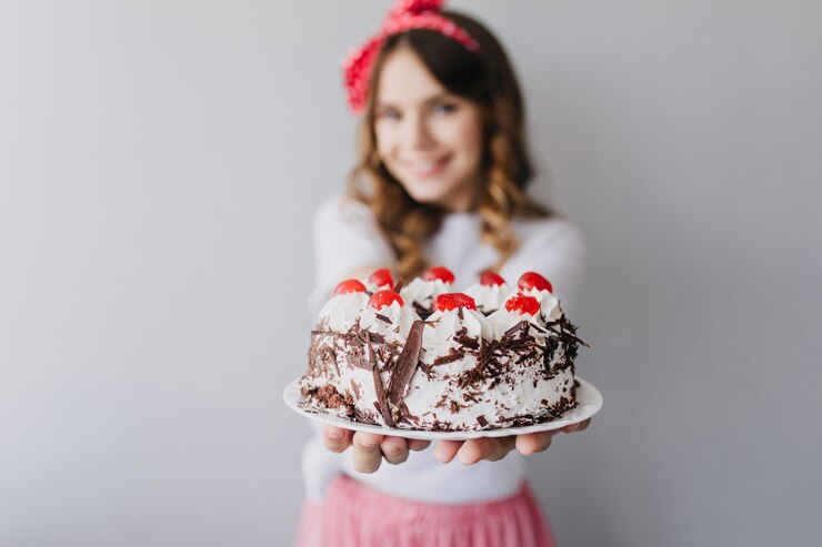 Foto grátis mulher caucasiana refinada mostrando saboroso bolo com frutas. retrato interior de uma deslumbrante aniversariante com torta cremosa.