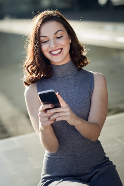 Mulher charming com um smartphone em um dia ensolarado