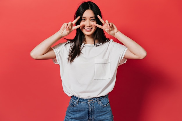 Mulher charmosa em uma camiseta estilosa sorrindo e mostrando sinais de paz