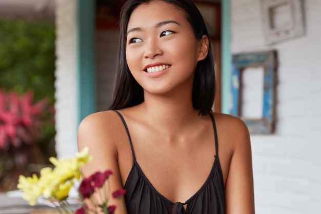 Mulher chinesa satisfeita e sorridente com pele saudável vestida casualmente em uma cafeteria