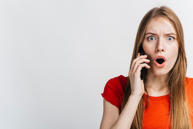 Mulher chocada falando no telefone com espaço de cópia