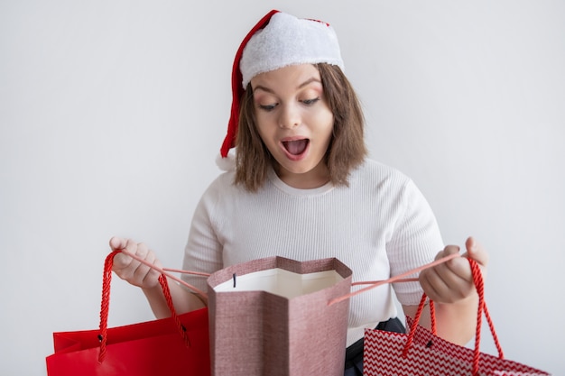 Mulher chocada no saco de abertura de chapéu de papai noel com presente de natal