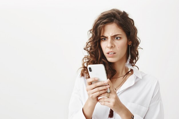 Foto grátis mulher chocada olhando frustrada para o celular