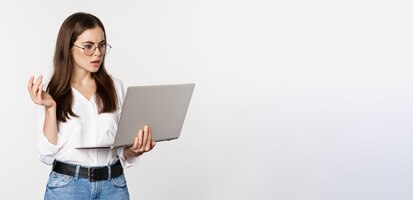 Foto grátis mulher chocada olhando para a tela do laptop confusa atordoada com smth no computador em cima de b branco