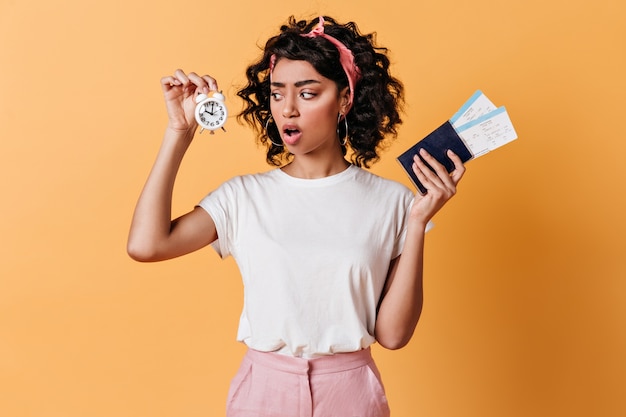 Foto grátis mulher chocada segurando passaporte e despertador