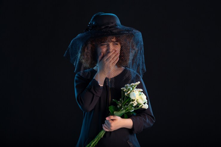 Foto grátis mulher chorando com flores vestida de preto em uma mesa preta luto pela morte no funeral